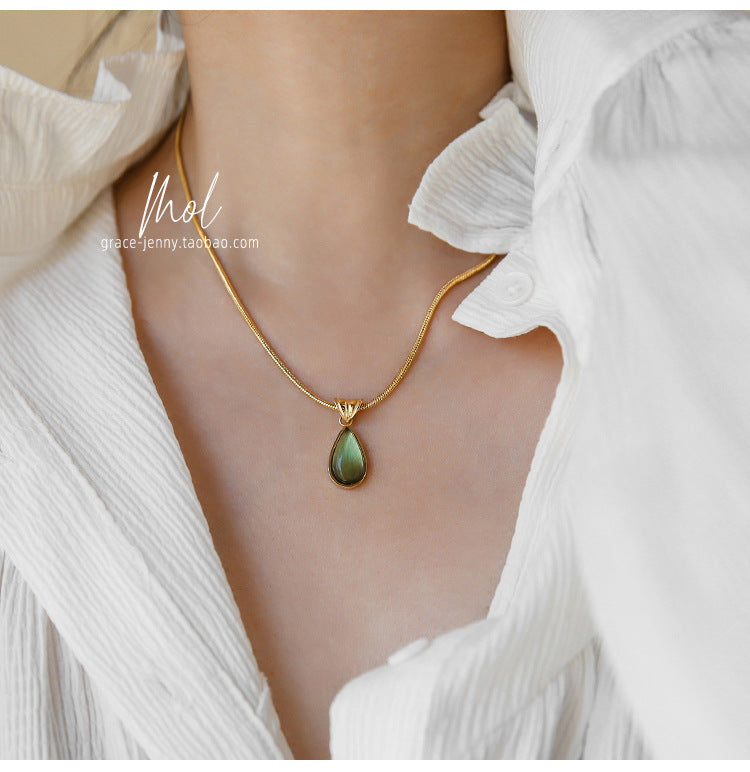 Gold-tone necklace with green teardrop crystal worn on the neck