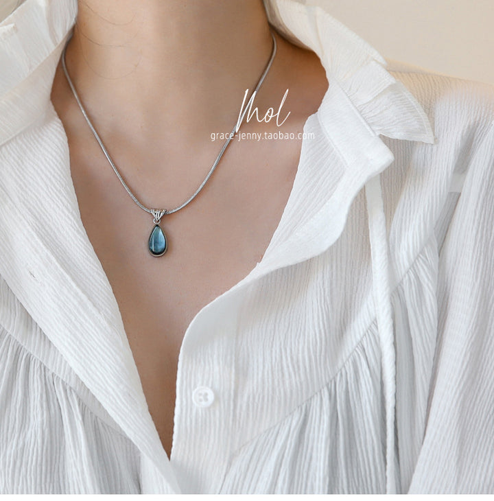 Silver-tone necklace with blue teardrop crystal worn on the neck