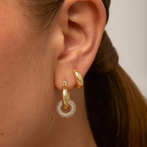 Close-up of gold pave halo drop hoop earring worn on ear