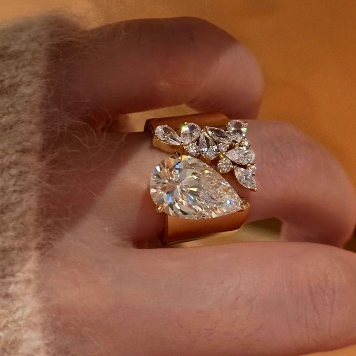 Gold pear-cut and floral cluster ring worn on a finger