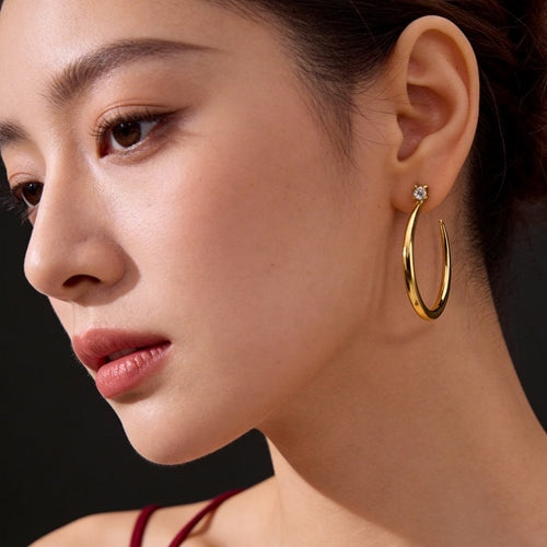Model wearing gold crescent hoop earrings