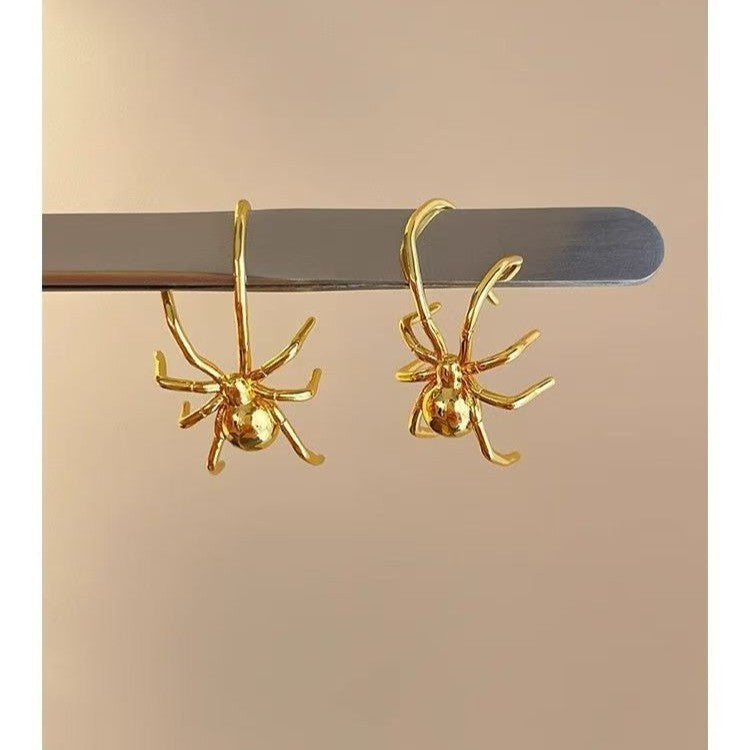 Pair of gold spider earrings on display