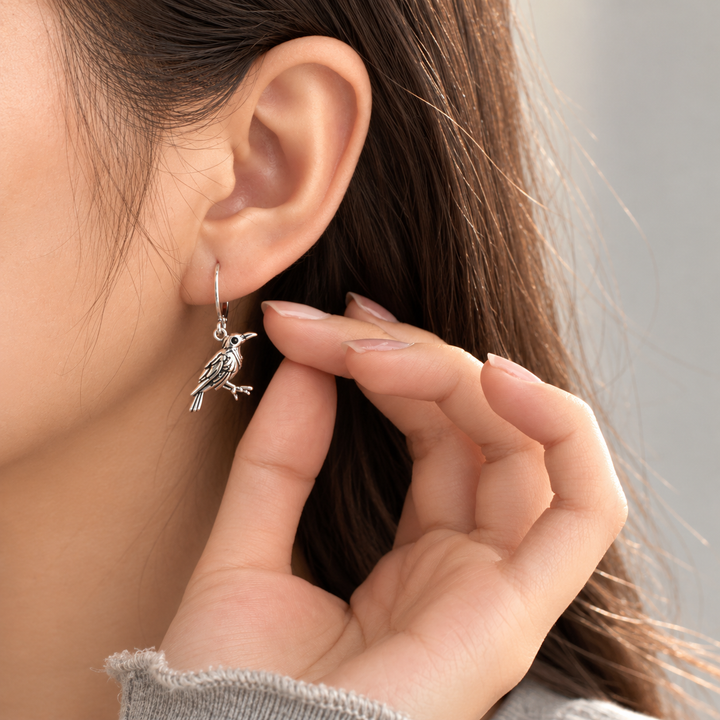 Model wearing a silver vintage raven drop earring